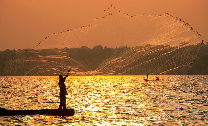 Fisherman casting his net at sunset on Lake Victoria