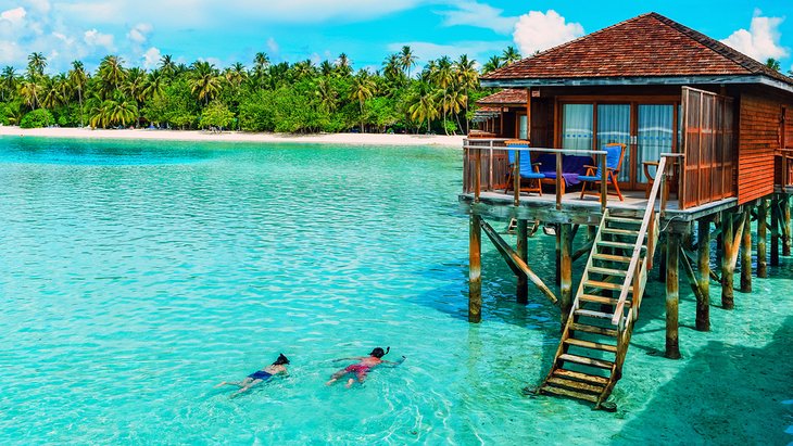 Couple snorkeling next to an over-the-water bungalow in the Maldives