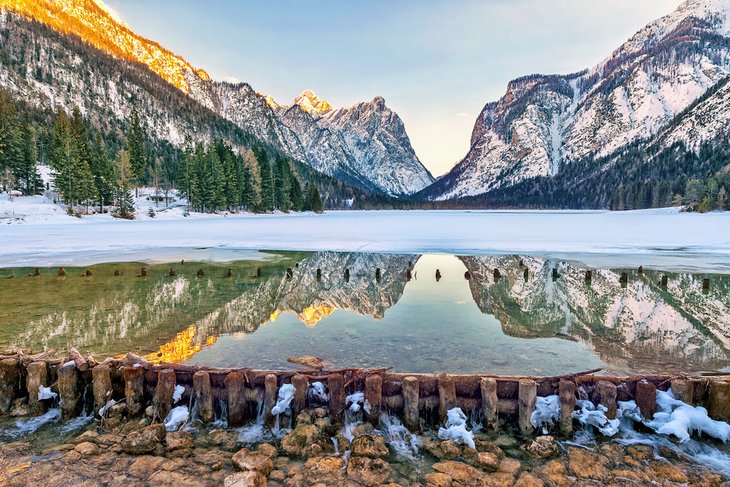 Iced lake with the Dolomites reflected on the water, Dobbiaco, Italy