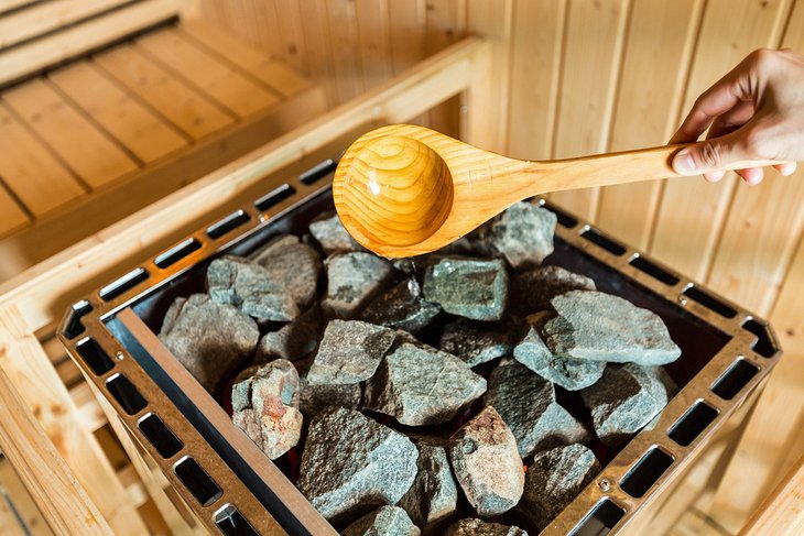 Pouring water over hot stones in a sauna