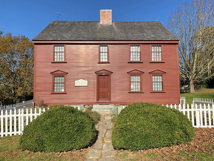 Ebenezer Avery House, flanked by lush bushes and a white picket fence