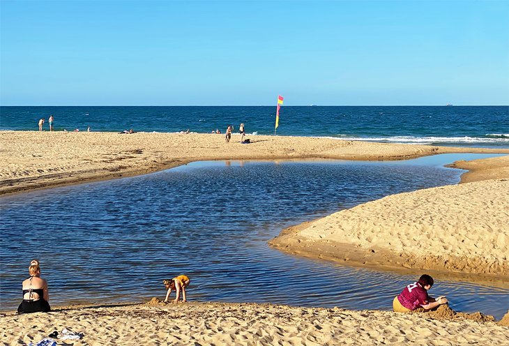 Children building sandcastles in Bunbubah Creek, Dicky Beach