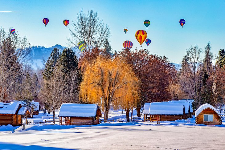 Hot air balloons over snow covered cabins in Winthrop
