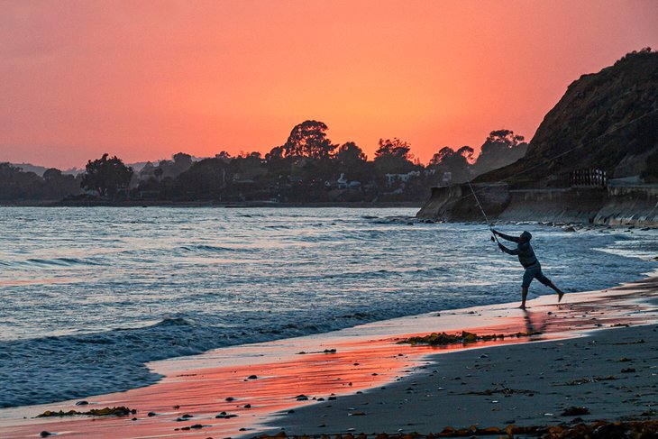 Fisherman casting off Summerland Beach at sunset