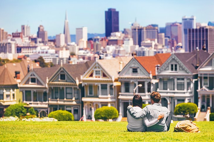 Couple relaxing in Alamo Park overlooking the Painted Ladies houses and downtown San Francisco
