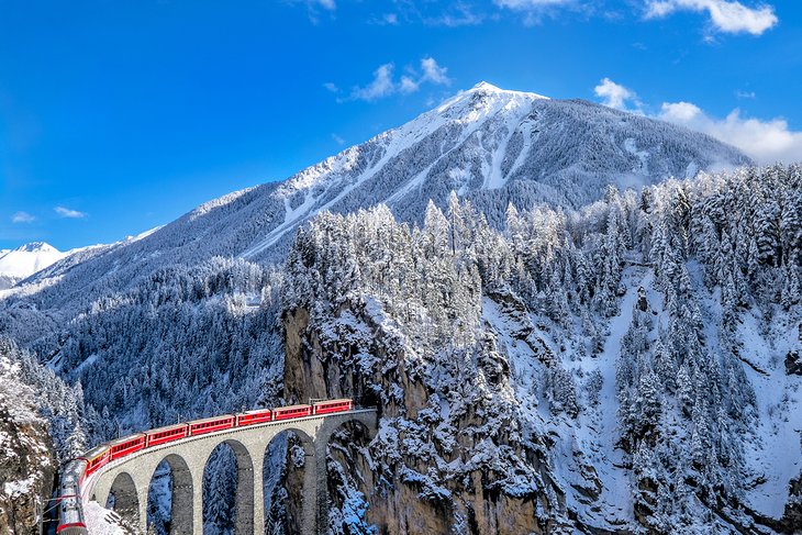 Glacier Express traveling through snowcapped mountains in Switzerland