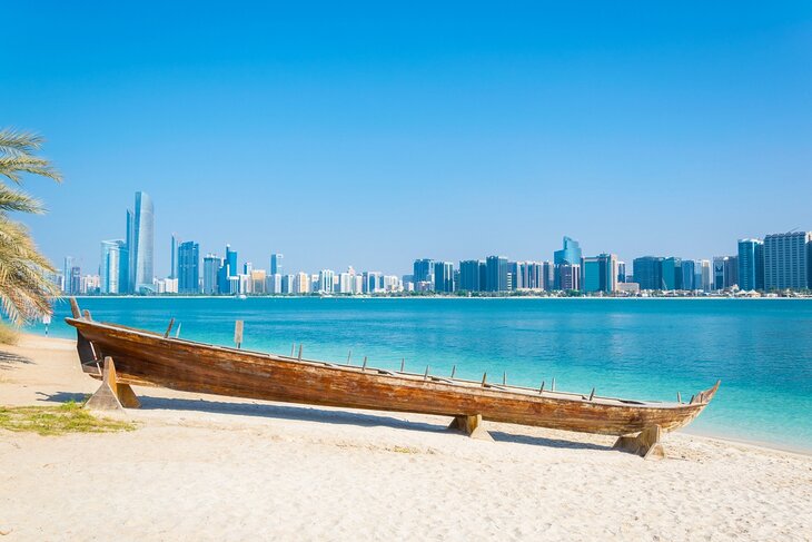 Wooden boat at the Heritage Village, in front of the Abu Dhabi skyline, United Arab Emirates