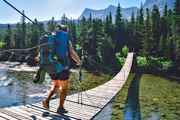 Backpacker on a suspension bridge on the Pacific Northwest National Scenic Trail in Glacier National Park