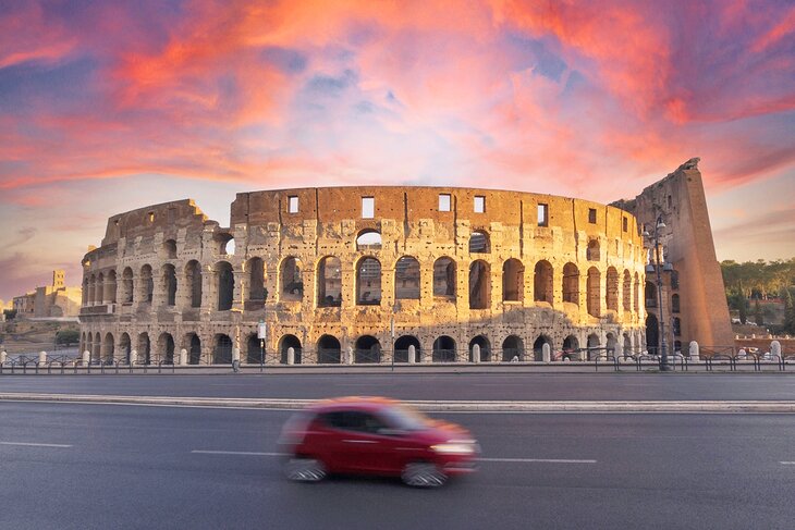 Car passing the Colosseum at sunset